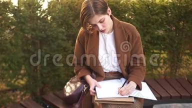 秋季春季考试，学生休息期间，返校.. 一个年轻的女学生在院子里写摘要